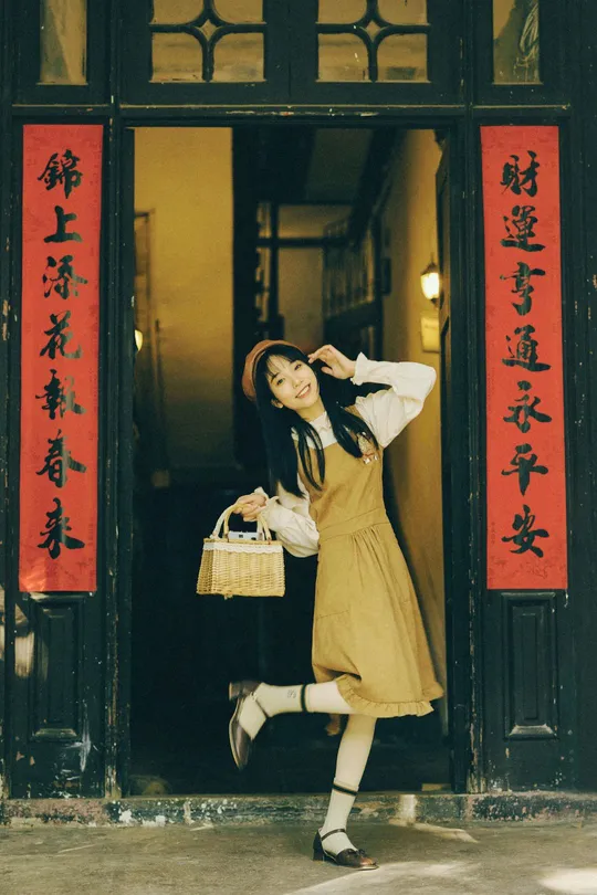 一位穿着黄色连衣裙的年轻女子抱着篮子走在建筑物前面