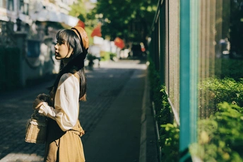 一位年轻女子抱着篮子走在人行道上