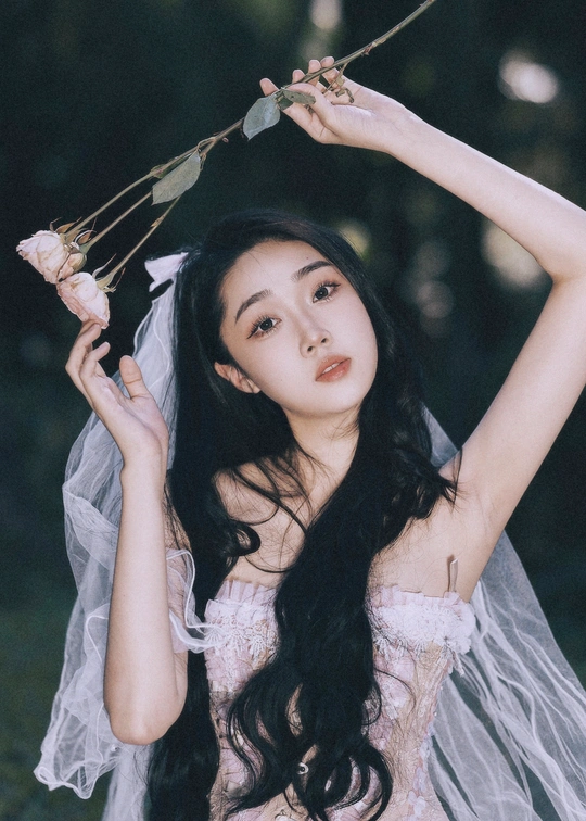 一位穿着白色长裙和面纱的美丽女子 手持一束花在森林中。