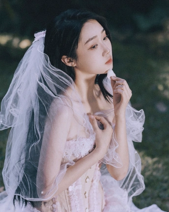 一位穿着白色长裙和面纱的女人站在外面