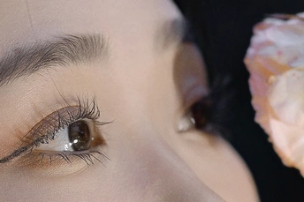 一个人用一只手拿着甜甜圈或点心 直接塞进嘴里 另一只手则托着她的眼睛。