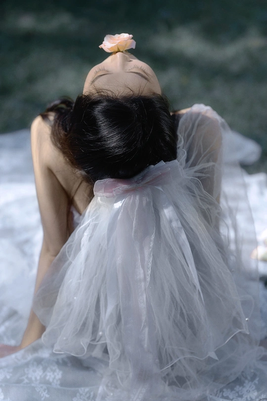 一位穿着白色连衣裙 头戴花的女青年坐在海水中