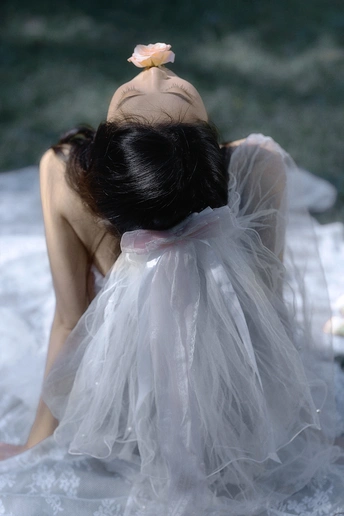 一位穿着白色连衣裙 头戴花的女青年坐在海水中