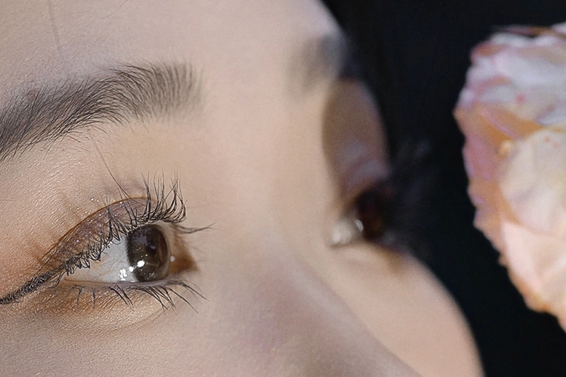 一个人用一只手拿着甜甜圈或点心 直接塞进嘴里 另一只手则托着她的眼睛。