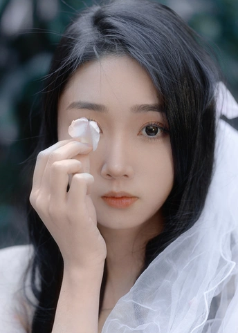 一个戴白色面纱遮住眼睛的年轻女子 鼻子上抹了白奶油。