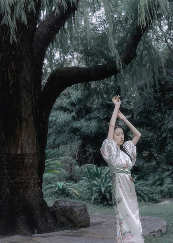 一位穿着传统裙子的年轻女子站在一棵树下