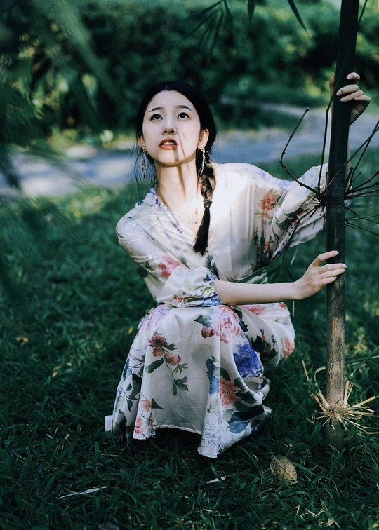 一位穿着和服的年轻女子拿着雨伞坐在树下