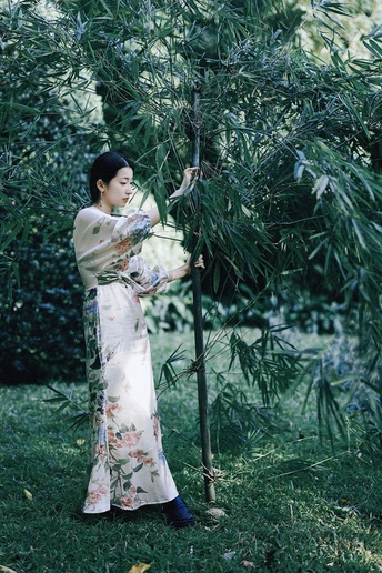一位穿着传统服装的年轻女子在花园里拿着一棵树。