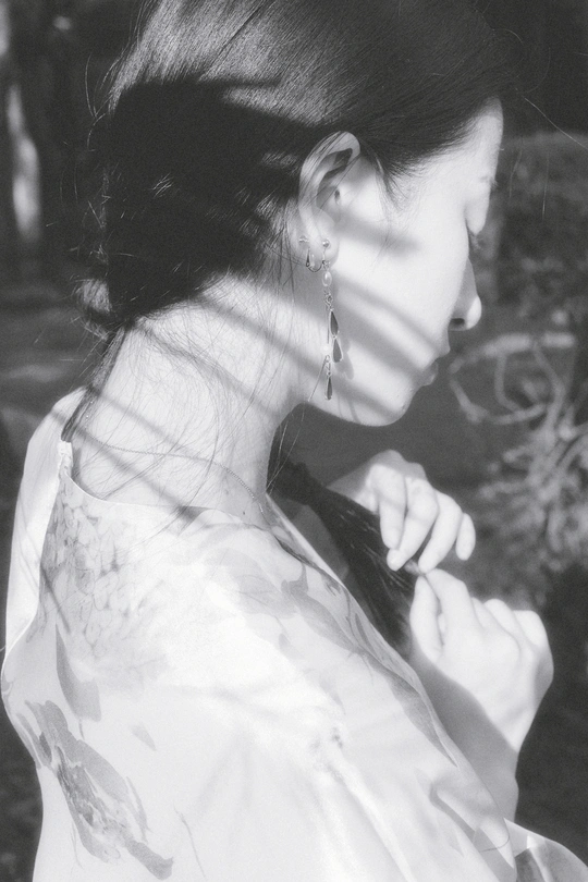 一张黑白照片 一位年轻女士穿着白色连衣裙 手持手机