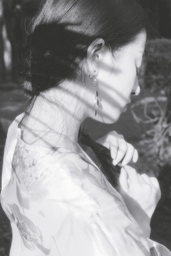 一张黑白照片 一位年轻女士穿着白色连衣裙 手持手机