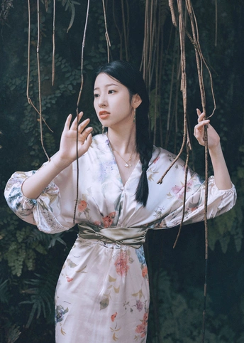 一位穿着和服的女士手持雨伞站在森林中的一棵树旁边