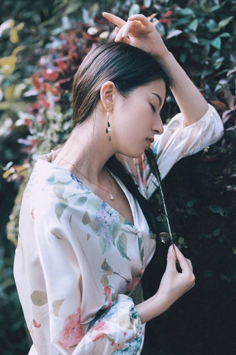 一位穿着和服的年轻女子手持雨伞 头戴鲜花。