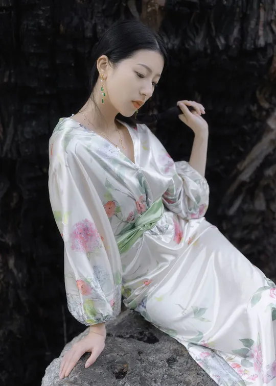 一位美丽的年轻女士穿着一件白色和服坐在岩石上