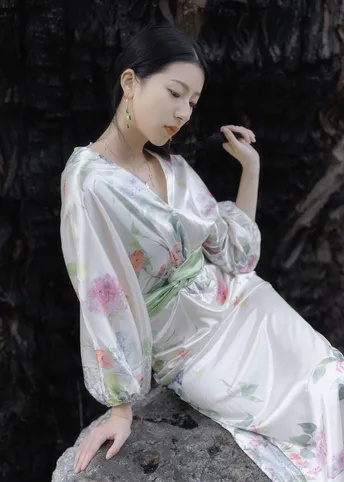 一位美丽的年轻女士穿着一件白色和服坐在岩石上