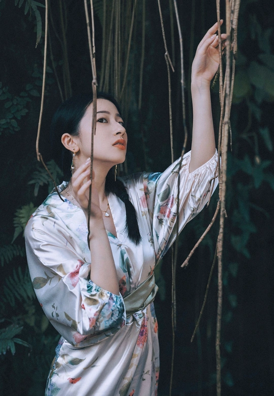 一位穿着和服的女子站在一棵棵树木组成的森林中