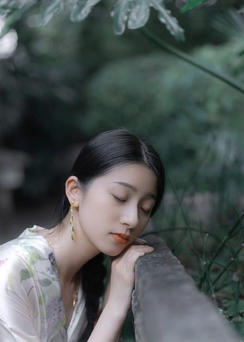 一位年轻女子正在一堵围墙旁边摆姿势