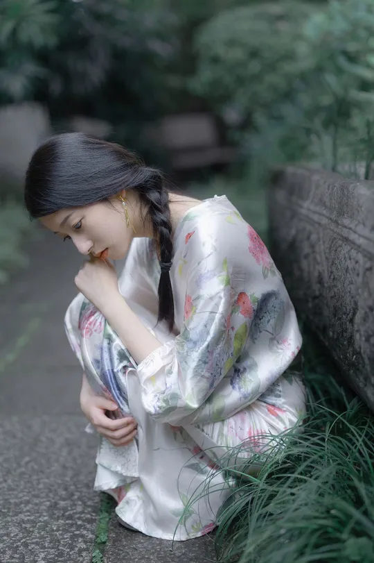 和服着装的年轻女子坐在石头小径上