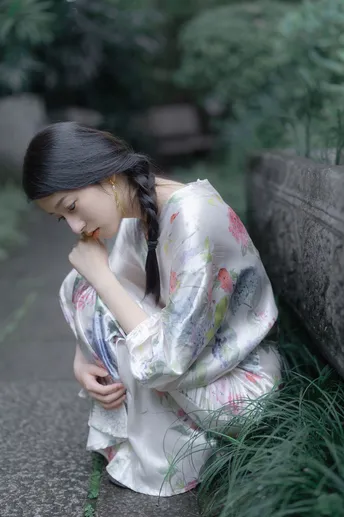 和服着装的年轻女子坐在石头小径上