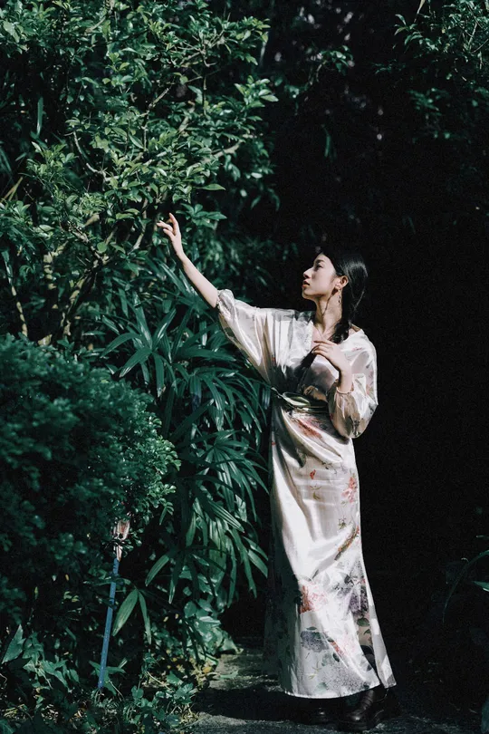 一位穿着和服的女士站在森林中 手里拿着一把雨伞