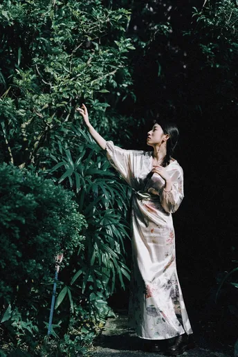 一位穿着和服的女士站在森林中 手里拿着一把雨伞