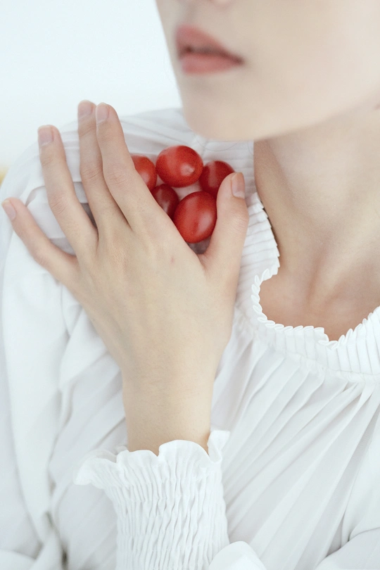 一位女子手里拿着一个红番茄