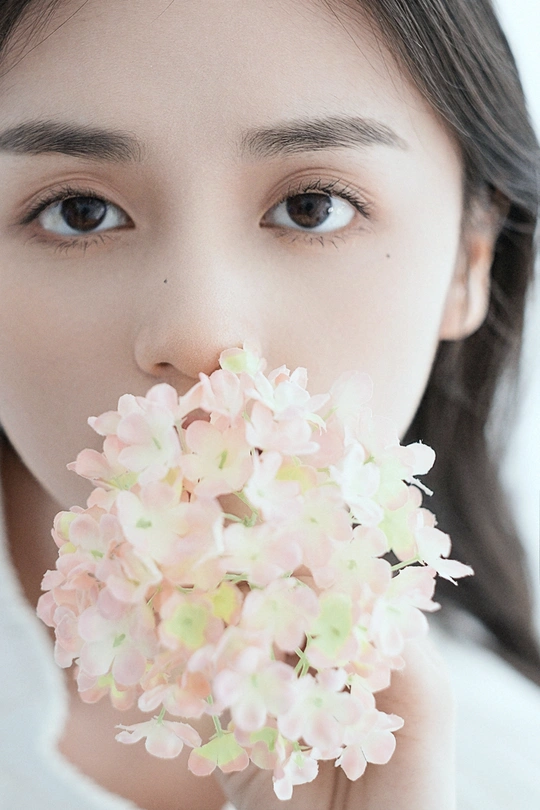 一位年轻女子抱着粉色花朵贴近脸庞的肖像