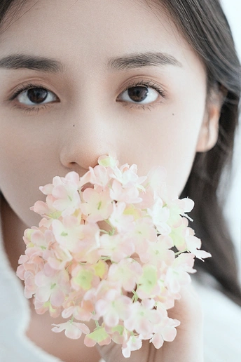 一位年轻女子抱着粉色花朵贴近脸庞的肖像