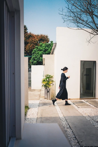 一个穿着黑色连衣裙的女人沿着人行道走向一所房子