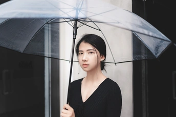 一个穿着黑色连衣裙的年轻女子拿着一把透明的雨伞