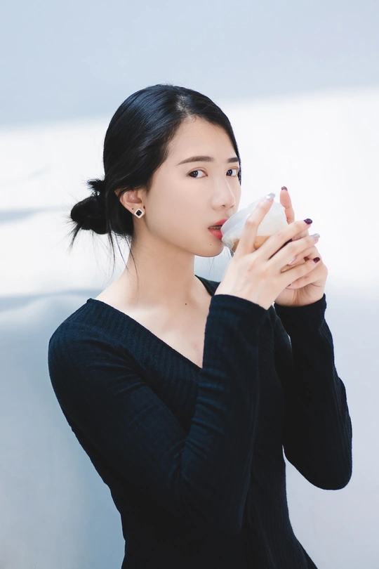 一个穿着黑色连衣裙的女人在杯子里喝酒