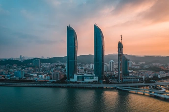 暮色和黄昏时分的繁华大都市 高耸的摩天大楼和摩天大楼 前景中有河流和桥。