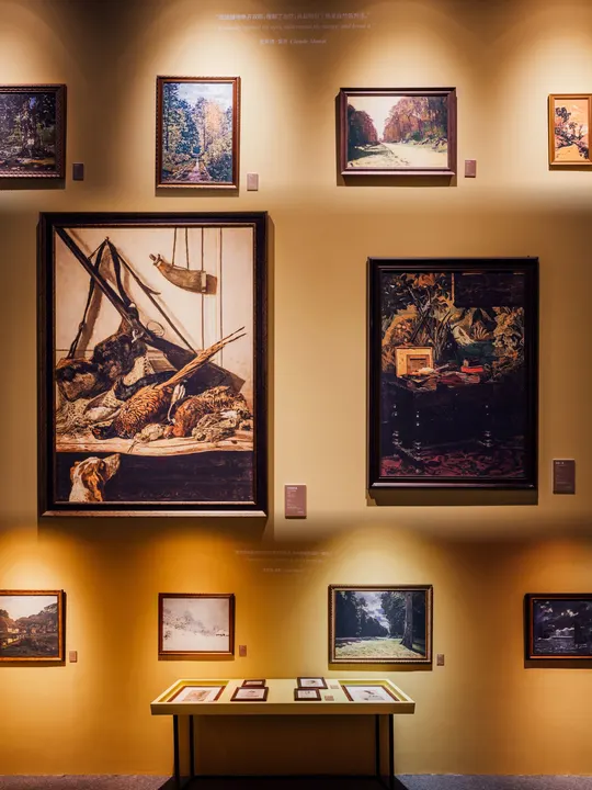 博物馆的一个展示柜 墙上挂着图片和画作。