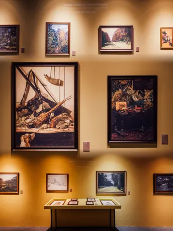 博物馆的一个展示柜 墙上挂着图片和画作。