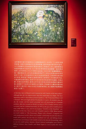 一面红色的墙 上面有一幅女人的画像和一幅花的画。