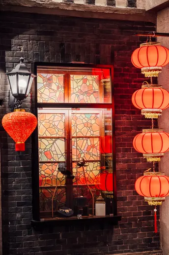 红灯笼挂在一堵砖墙上窗户前