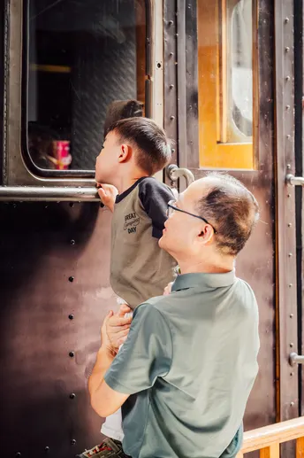 一个抱着小男孩站在火车门旁的男人 另一个男人正在看着