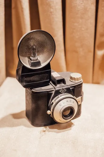 桌子上放着一台老式相机 前面有一扇窗帘。