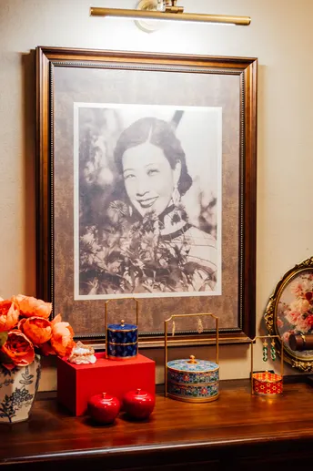 一张桌子上的女人照片 周围有花瓶、蜡烛和一幅画框肖像。