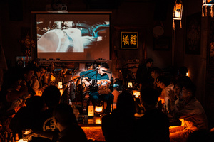 人们在酒吧里观看一个在大屏幕上的乐队表演。