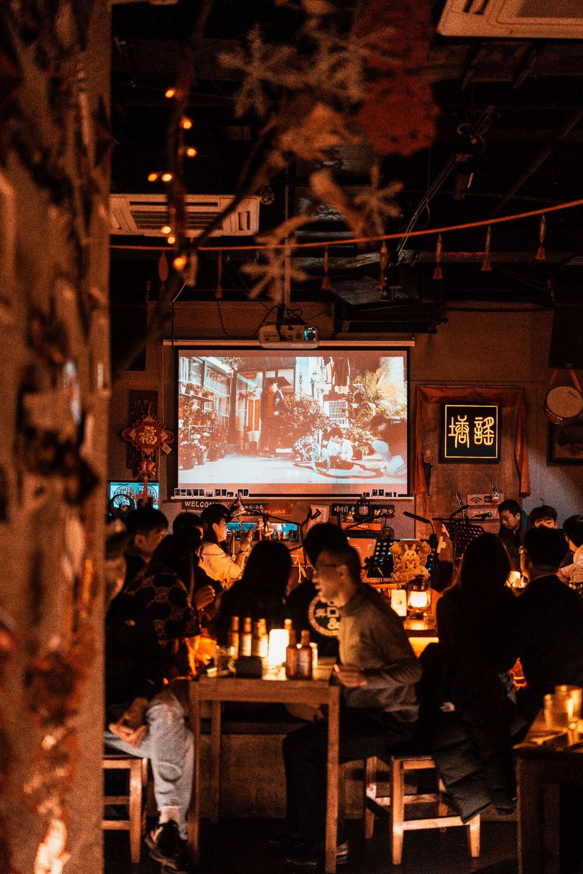 人们在餐厅的桌子旁观看一部大型电视上的电影。