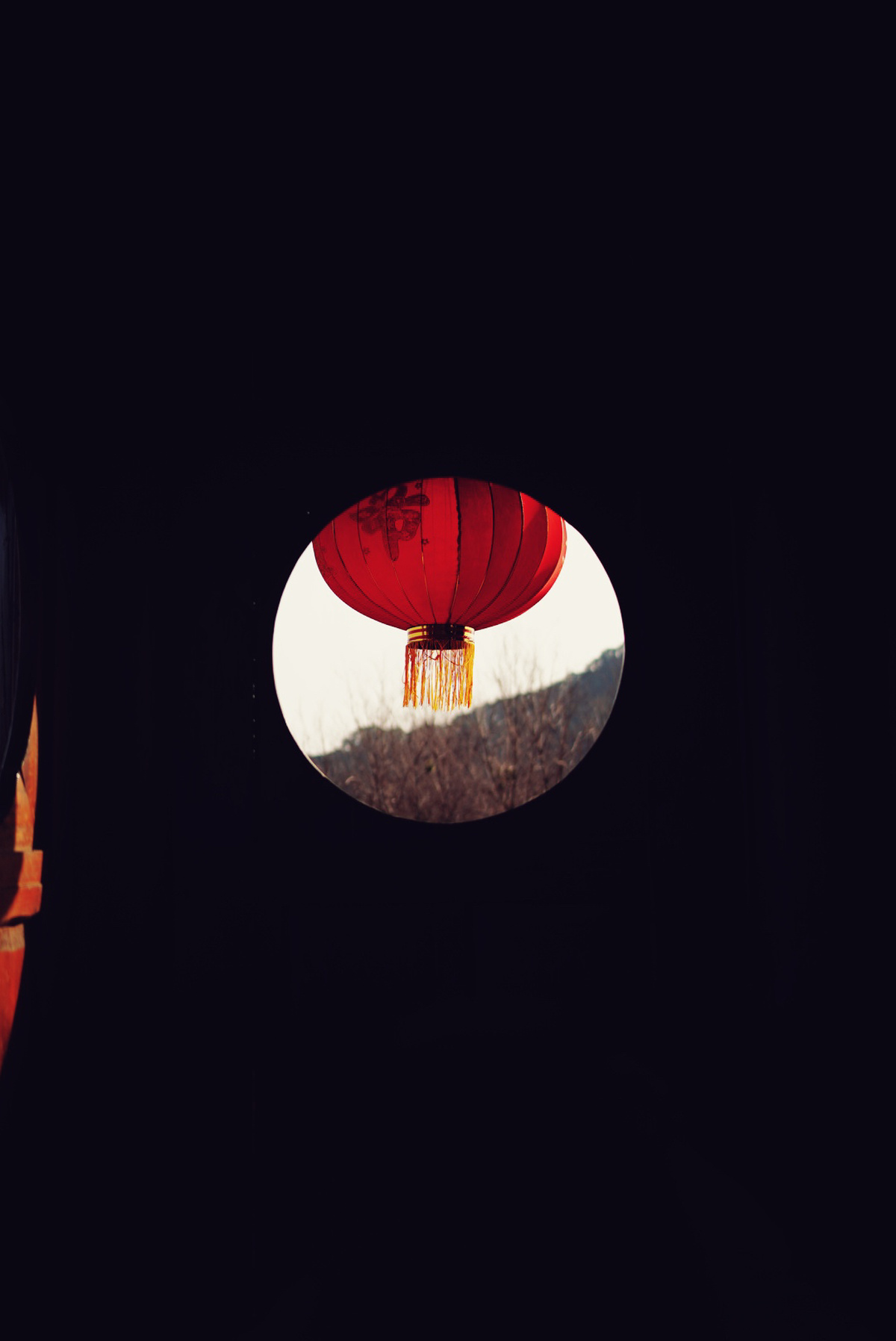 一个红色的中国灯笼在黑暗的窗户里