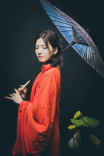 一位穿着红色连衣裙的年轻女子手持蓝色雨伞
