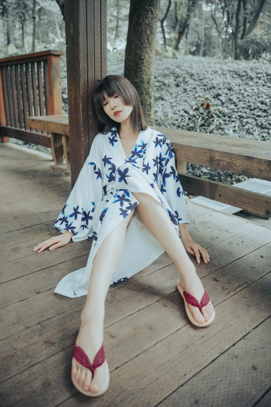 一个穿着和服和红鞋子的年轻女人坐在门廊的木长椅上