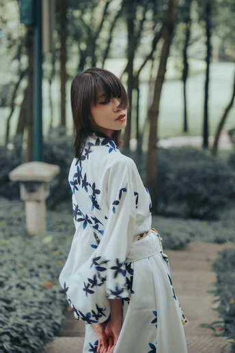 一个穿着白色连衣裙和碎花和服的女人站在小路上