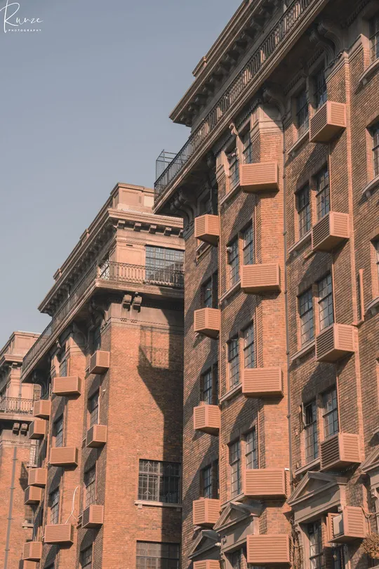 城市中的一座高大的红砖建筑 带有阳台。