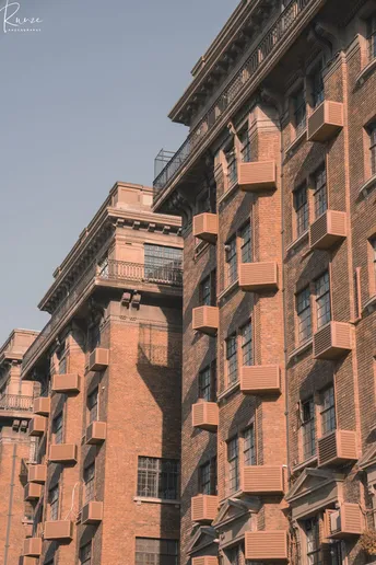 城市中的一座高大的红砖建筑 带有阳台。