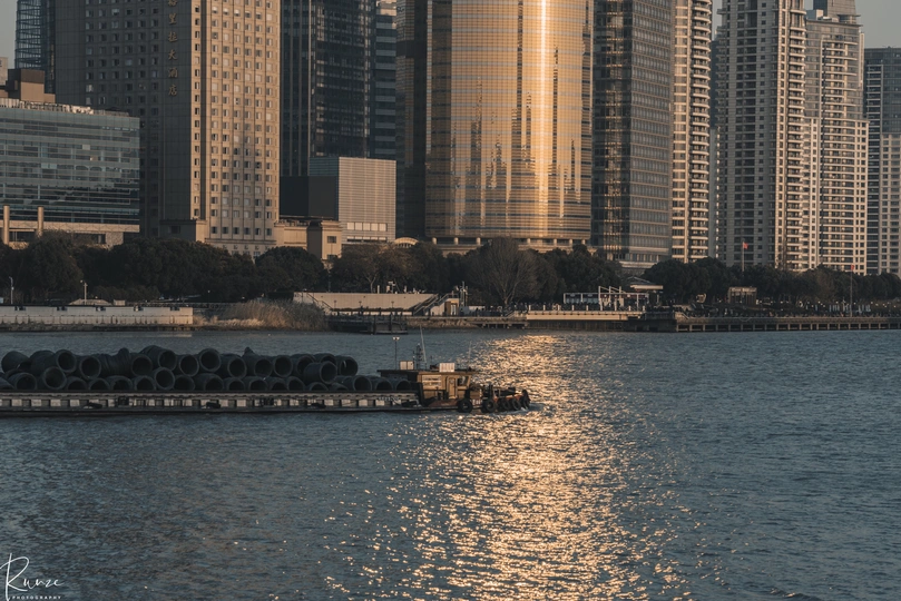 城市前方有一大片水域 高耸的建筑物在阳光穿过天际线时显得格外壮观。