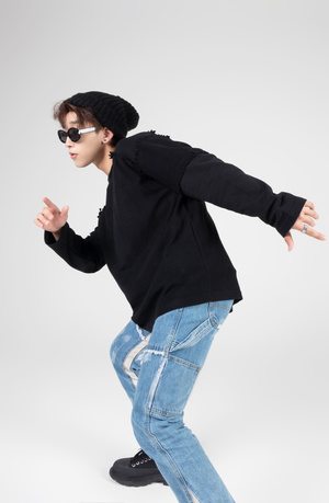 一个戴黑色贝雷帽、太阳镜和黑色帽子的年轻人正在滑滑板跳舞。