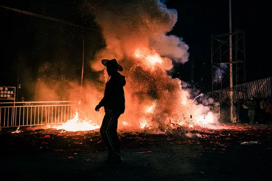 一个人在剪影中走过一个熊熊大火堆 夜晚有火焰。