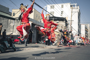 穿着红衣服的舞者在街上跳舞 而其他人则在背景中跳舞。